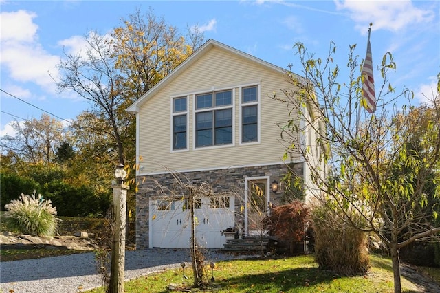 view of front of home featuring gravel driveway, stone siding, and an attached garage