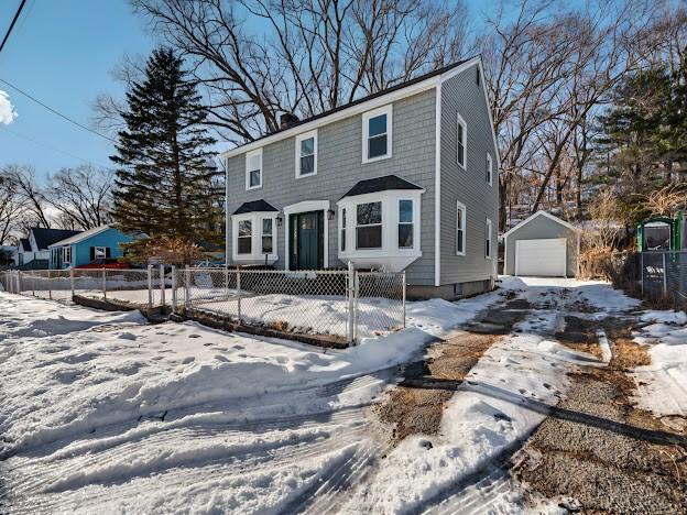 colonial inspired home with a garage, fence private yard, an outdoor structure, and a chimney