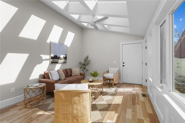 sitting room with ceiling fan, vaulted ceiling with skylight, light wood-type flooring, and visible vents