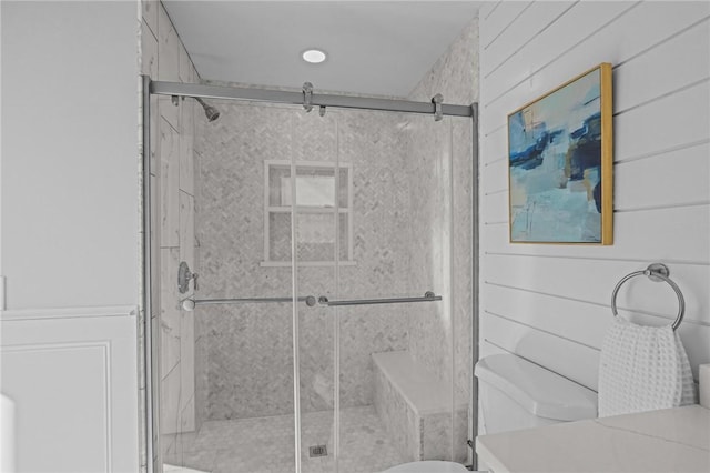 bathroom with toilet, a shower stall, and wooden walls