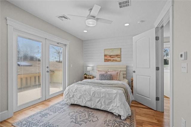 bedroom featuring access to outside, visible vents, and wood finished floors