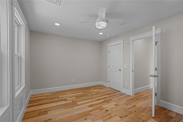 empty room featuring a ceiling fan, light wood-type flooring, visible vents, and baseboards