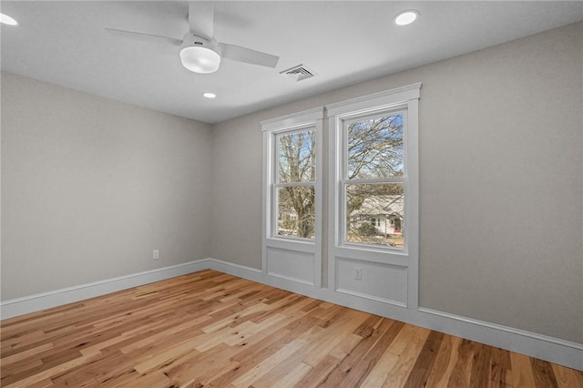 empty room featuring light wood-style floors, visible vents, baseboards, and a ceiling fan