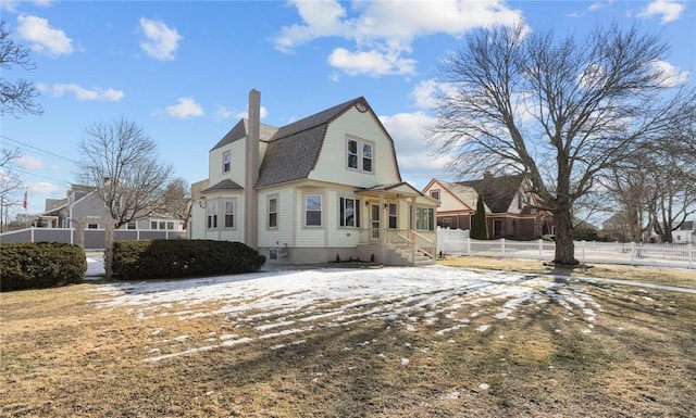 view of front of property featuring a chimney, a residential view, fence, and a gambrel roof