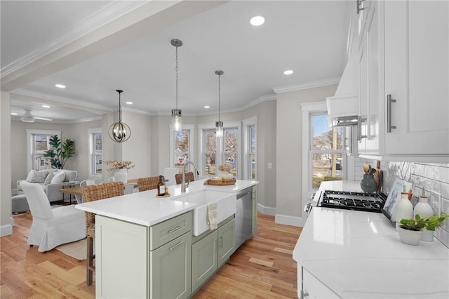 kitchen with a sink, light countertops, dishwasher, an island with sink, and a kitchen bar