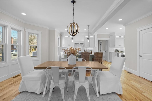 dining room featuring light wood-type flooring, a notable chandelier, visible vents, and crown molding