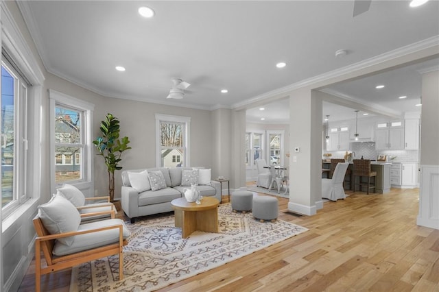 living area with light wood-type flooring, plenty of natural light, ornamental molding, and recessed lighting