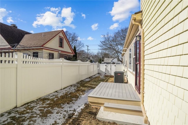 exterior space featuring central AC unit, a fenced backyard, and a gate