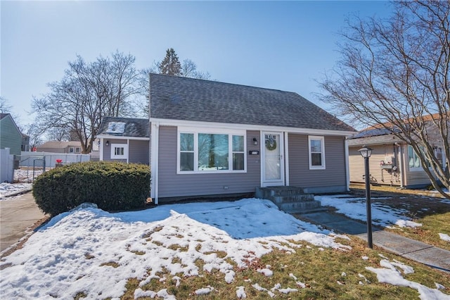 view of front of house with roof with shingles and fence