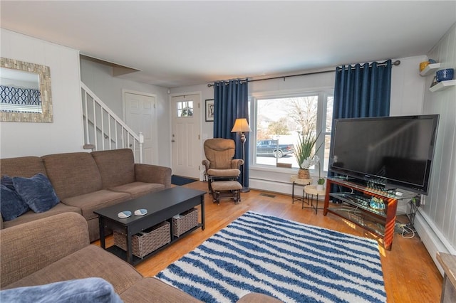 living room with stairway, wood finished floors, and visible vents