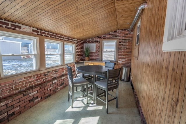 dining area with wooden ceiling, vaulted ceiling, and brick wall