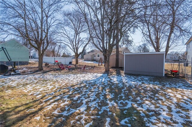 yard covered in snow featuring an outbuilding, fence, a residential view, and a shed