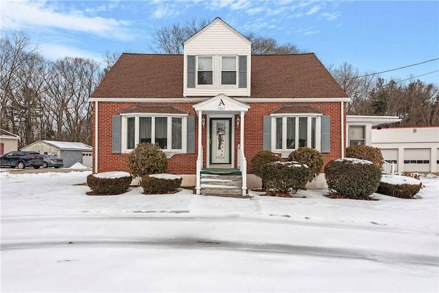 view of front facade featuring brick siding and roof with shingles