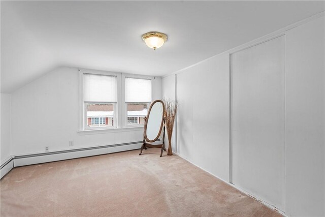 additional living space featuring a baseboard heating unit, light colored carpet, and vaulted ceiling