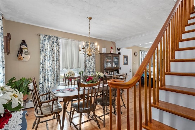 dining room with light wood finished floors, stairway, baseboard heating, and a notable chandelier