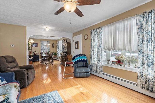 living room with a baseboard radiator, arched walkways, and wood finished floors