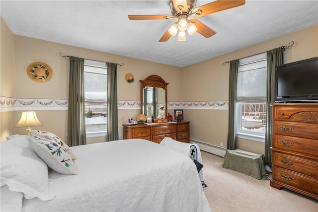 bedroom featuring multiple windows, baseboard heating, a ceiling fan, and light colored carpet