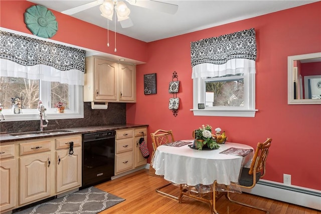 kitchen featuring light wood finished floors, baseboard heating, light brown cabinets, a sink, and dishwasher