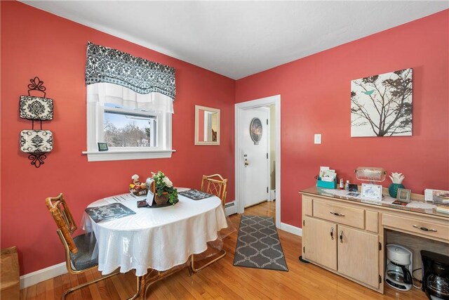 dining room featuring a baseboard radiator, light wood-style flooring, and baseboards