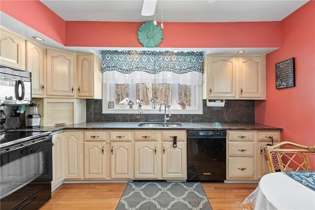 kitchen featuring light wood-style floors, a sink, black appliances, and tasteful backsplash