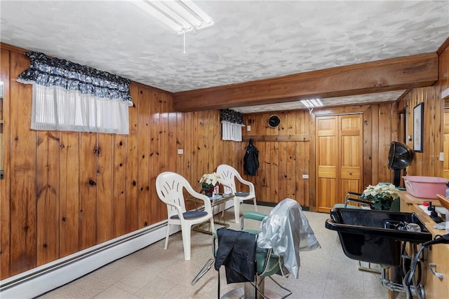 interior space with light floors, a baseboard heating unit, and wood walls