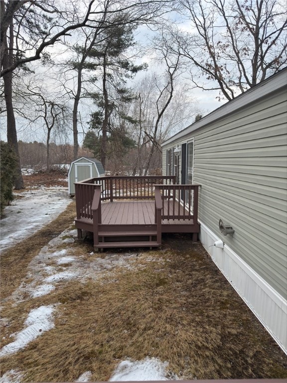 snow covered deck featuring a shed and an outdoor structure