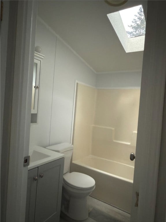 bathroom featuring vaulted ceiling with skylight, shower / bathing tub combination, vanity, and toilet