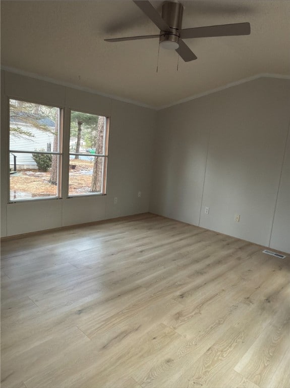 unfurnished room with ceiling fan, visible vents, light wood-style floors, vaulted ceiling, and crown molding