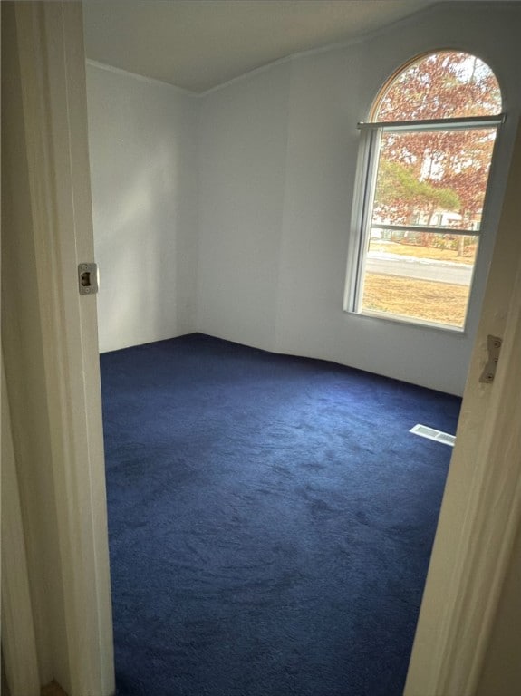 unfurnished room featuring visible vents and dark colored carpet