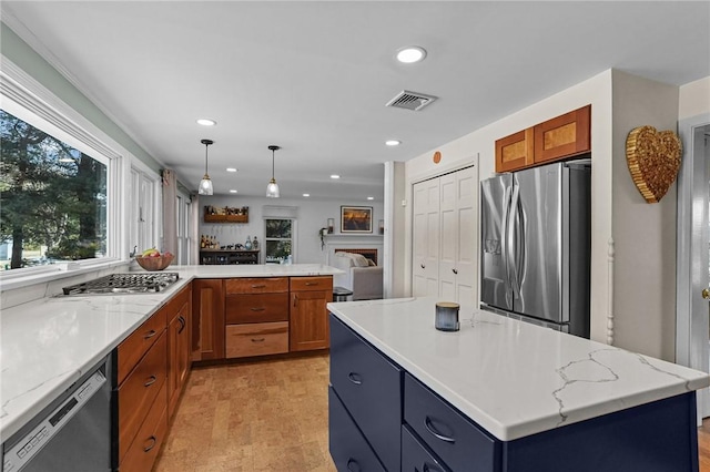 kitchen with open floor plan, stainless steel appliances, a peninsula, and brown cabinets