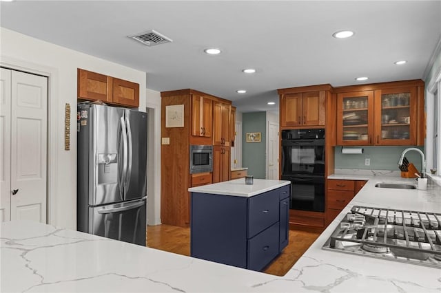 kitchen featuring light stone countertops, visible vents, stainless steel appliances, and a sink