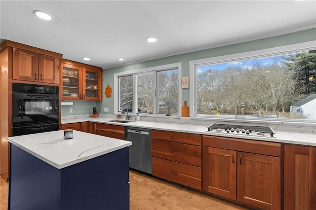 kitchen with light stone counters, recessed lighting, appliances with stainless steel finishes, glass insert cabinets, and a sink