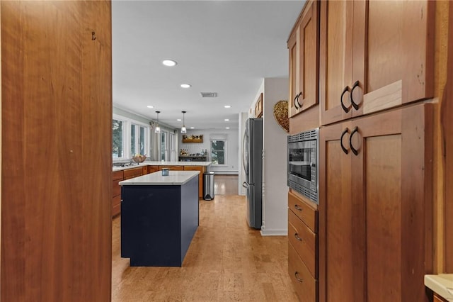 kitchen with visible vents, brown cabinetry, a kitchen island, appliances with stainless steel finishes, and light countertops