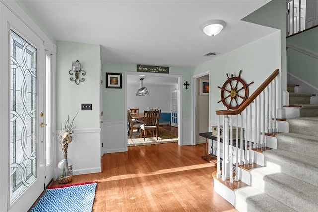 foyer entrance with stairway, visible vents, and wood finished floors