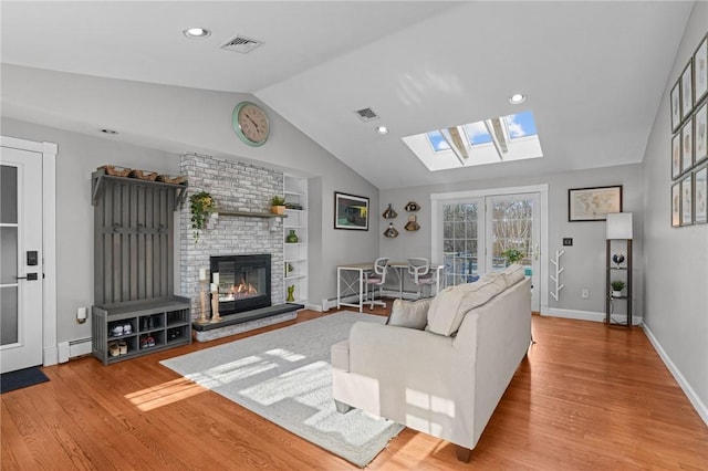 living area with visible vents, vaulted ceiling, and wood finished floors