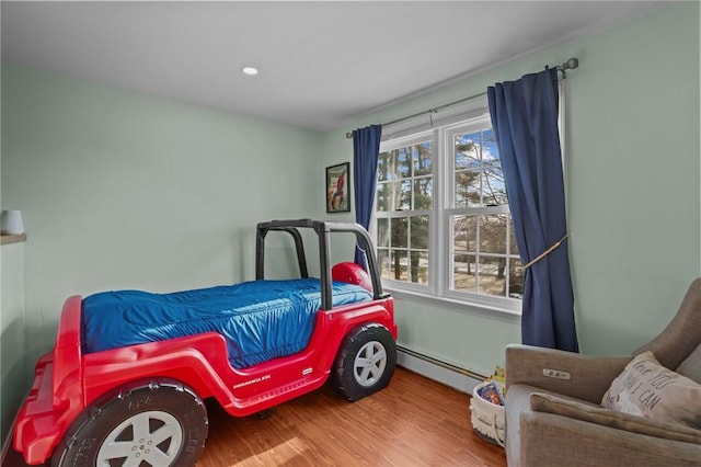 bedroom with recessed lighting, baseboard heating, and wood finished floors