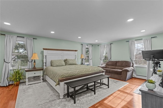 bedroom featuring light wood-type flooring, a baseboard radiator, and recessed lighting