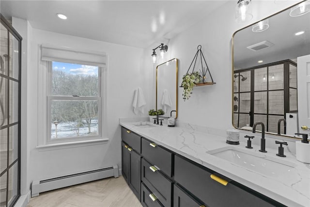 full bath featuring double vanity, visible vents, baseboard heating, and a sink