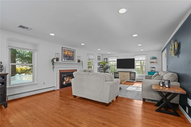 living area with visible vents, a fireplace, light wood finished floors, and baseboard heating