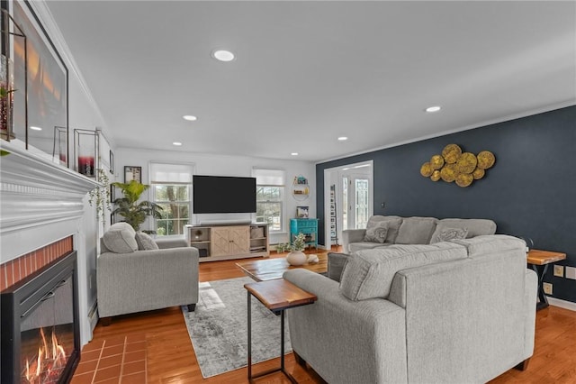 living area featuring crown molding, a lit fireplace, and wood finished floors