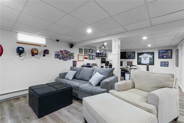 living area with a baseboard heating unit, recessed lighting, a drop ceiling, and wood finished floors