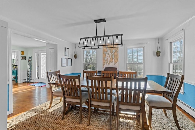 dining room with a healthy amount of sunlight, a baseboard radiator, and wood finished floors