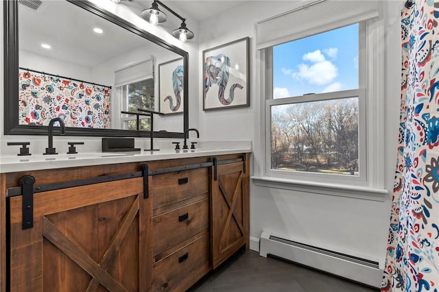 bathroom with double vanity, a baseboard radiator, a sink, and visible vents