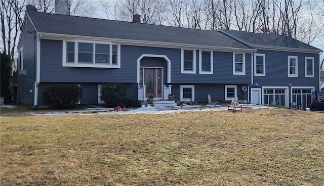 bi-level home with a garage, a chimney, and a front lawn