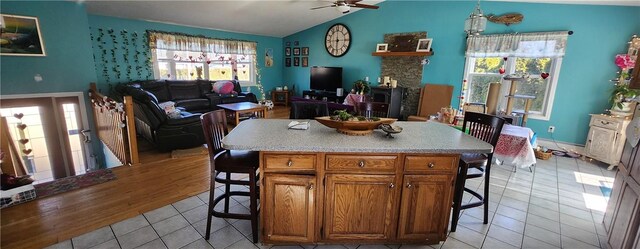 kitchen featuring a breakfast bar, brown cabinetry, plenty of natural light, and vaulted ceiling