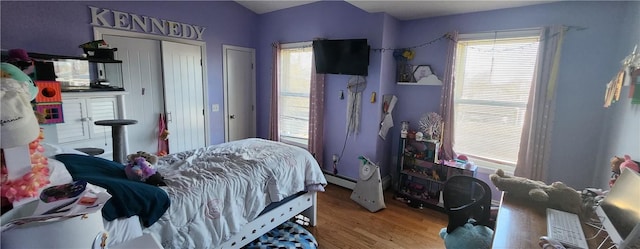 bedroom featuring a baseboard heating unit and wood finished floors