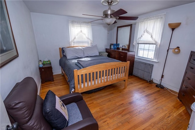 bedroom with ceiling fan, radiator heating unit, and light wood-style flooring