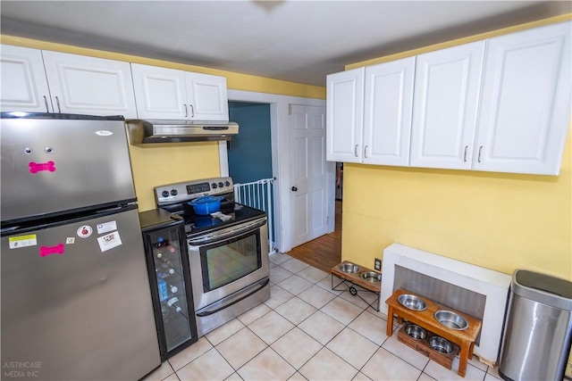 kitchen with light tile patterned floors, appliances with stainless steel finishes, white cabinetry, and under cabinet range hood