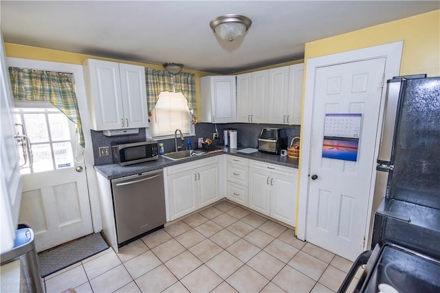 kitchen featuring tasteful backsplash, dark countertops, appliances with stainless steel finishes, white cabinetry, and a sink