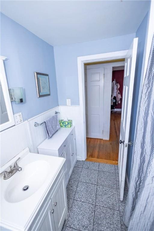 bathroom featuring wainscoting, granite finish floor, and vanity